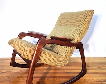 May include: A mid-century modern rocking chair with a woven beige and brown fabric seat and back. The chair has curved, dark wood arms and rockers. The text "PROREFINE FURNISHINGS" is displayed at the top of the image.