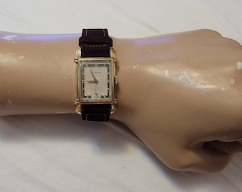 Relógio masculino vintage Wittnauer 3315-G6 com asas sofisticadas, mostrador retangular preenchido com tecido e detalhes em ouro 10K, corda manual.