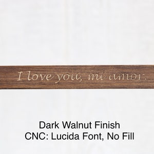 May include: A dark walnut wood sign with the text "I love you, mi amor." engraved in a Lucida font. The sign has a smooth finish and no fill.