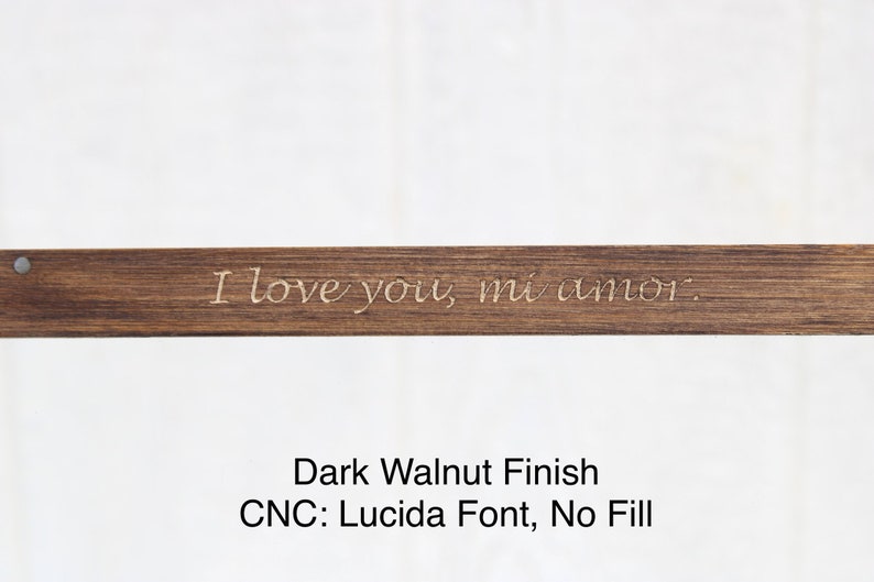 May include: A dark walnut wood sign with the text "I love you, mi amor." engraved in a Lucida font. The sign has a smooth finish and no fill.