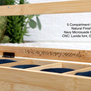 May include: A wooden watch box with a glass top and five compartments lined with navy blue fabric. The box has a natural finish and is engraved with the text "I love you every second".