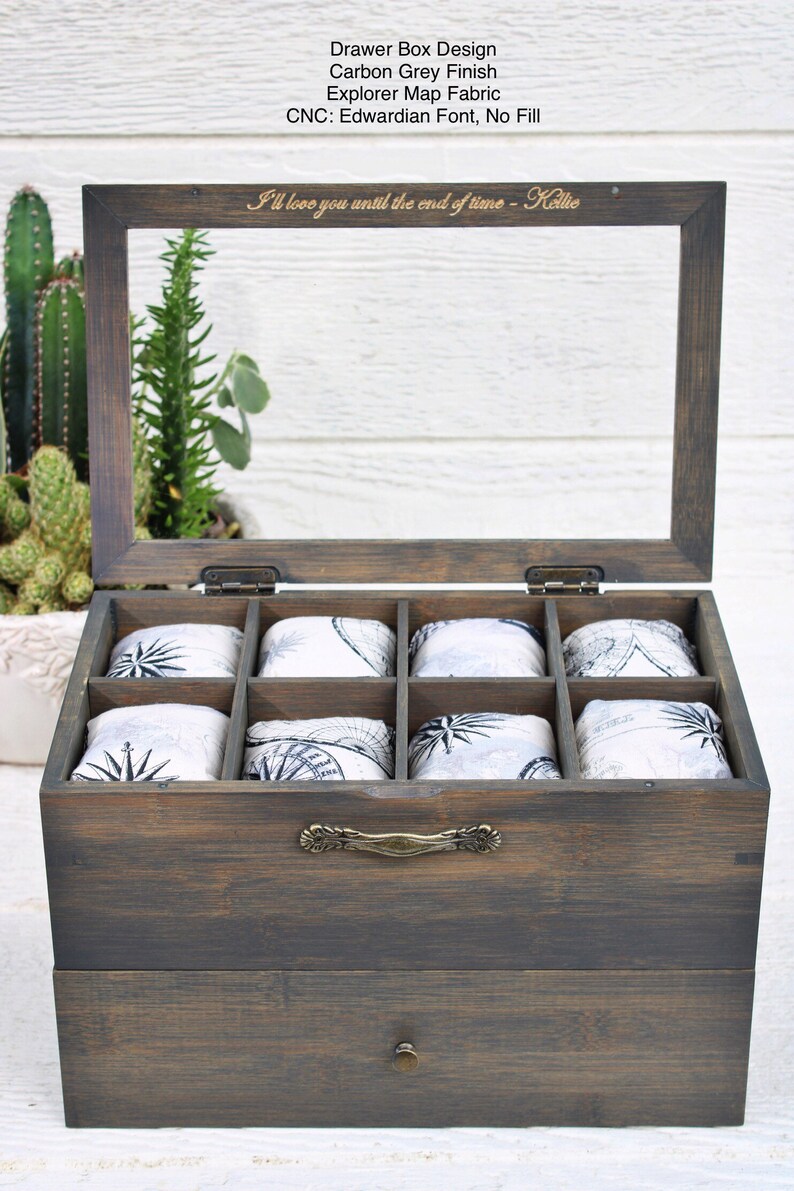May include: A wooden drawer box with a glass top and a pull-out drawer. The box has eight compartments lined with fabric featuring a compass design. The top of the box is engraved with the text "I'll love you until the end of time - Kellie".