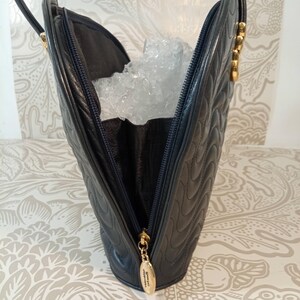 May include: A dark navy blue leather handbag featuring a quilted wave pattern on the exterior. The bag has a top zipper closure with a gold-toned metal pull tab engraved with the text Valentino Orlandi and two thin matching leather shoulder straps.