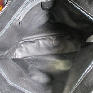 May include: The inside of a black leather tote bag with a zipper closure. The bag has a black fabric lining.