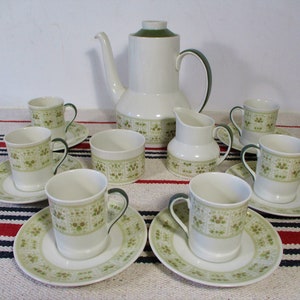 Puede incluir: Un juego de té vintage con un patrón floral verde y blanco. El juego incluye una tetera, una jarra de crema, un azucarero y seis tazas y platillos.