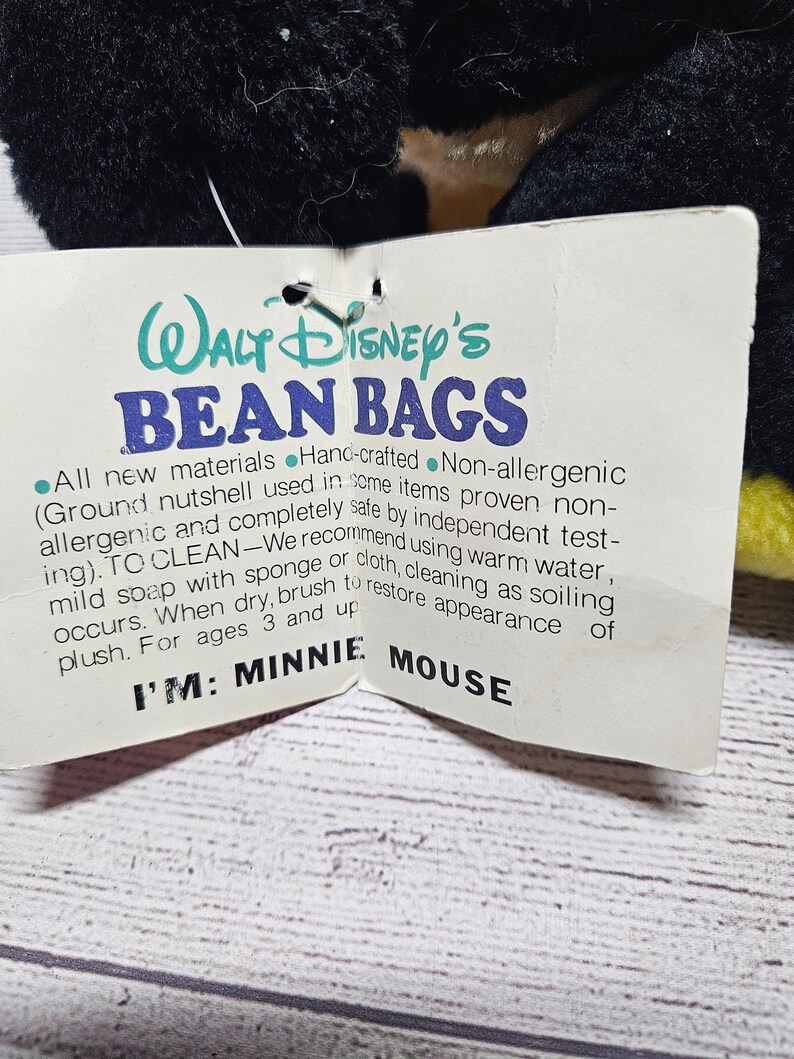 May include: A black plush toy with a tag that reads "Walt Disney's Bean Bags". The tag also says "I'M: MINNIE MOUSE". The plush toy has black fur and yellow accents.