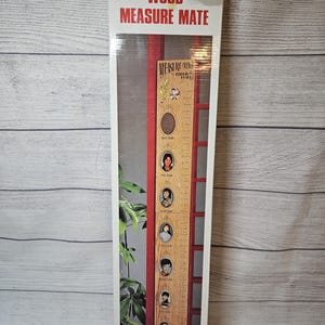 May include: A Heartland Wood Measure Mate growth chart in its original packaging. The chart is a wooden ruler with a red frame and space for photos. The packaging has the words "Wood Measure Mate" in red and white.