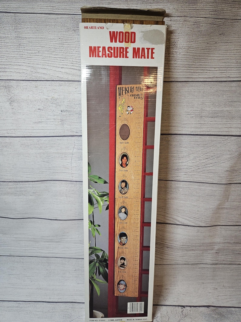 May include: A Heartland Wood Measure Mate growth chart in its original packaging. The chart is a wooden ruler with a red frame and space for photos. The packaging has the words "Wood Measure Mate" in red and white.