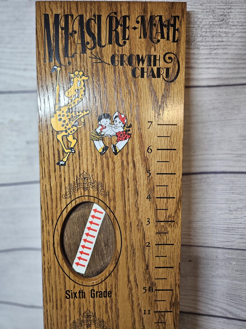 May include: Wooden growth chart with the text "Measure-Mate Growth Chart." Features illustrations of a giraffe and children. Includes a Sixth Grade label and height markings in feet.