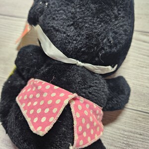 May include: A vintage black plush toy with a white ribbon and a pink polka dot scarf. The plush toy is made of a soft, fuzzy material and has a classic design. The toy is in good condition and would make a great addition to any collection.