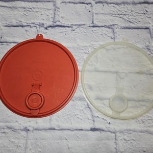 May include: A white ceramic mug with a black handle and the text "But First, Coffee" in a bold, black font. The mug is set against a blurred background, suggesting a cozy setting.