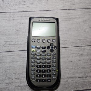 May include: A TI-89 Titanium calculator by Texas Instruments. The calculator has a black and gray design with numerous buttons and a screen. The calculator is designed for advanced mathematical functions.