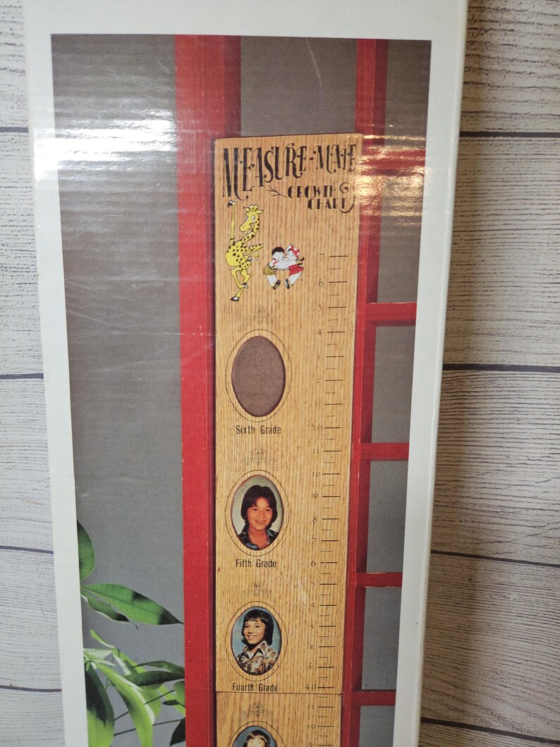 May include: Wooden height chart with the text "Measure-Me" and "Growing Chart". It features a giraffe and two children illustrations. Includes photo frames for each grade level, from fourth to sixth grade.