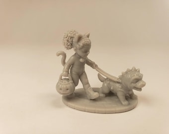 Puede incluir: Una figura de resina gris monocromática que representa a un niño disfrazado de gato con orejas y cola, sosteniendo un cubo de calabaza mientras pasea a un perro pequeño con pinchos con una correa. La escena se asienta sobre una base circular.