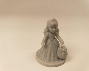 Puede incluir: Una figura de resina gris monocromática de un personaje con un vestido largo plisado con detalles intrincados en el dobladillo, una tiara y cabello largo. El personaje sostiene una pequeña cesta redonda con un diseño de corazón.