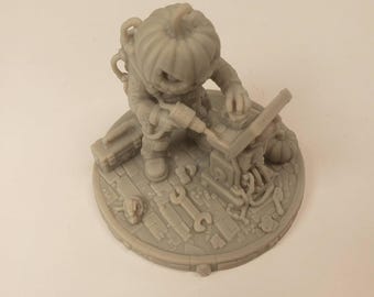 Puede incluir: Una figura miniatura de resina gris claro que representa un personaje con cabeza de calabaza y traje espacial. La figura está sobre una base circular, sosteniendo un taladro mientras trabaja en un dispositivo mecánico rodeado de herramientas.