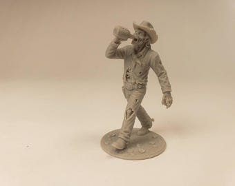 Puede incluir: Una miniatura de resina de color gris claro sin pintar de un vaquero zombi con sombrero de ala ancha, pañuelo al cuello y ropa desgarrada. La figura camina hacia adelante mientras sostiene una botella en la boca sobre una base circular.