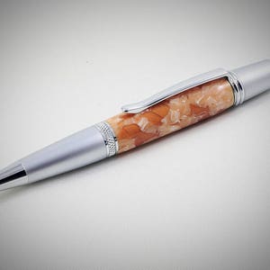 May include: A silver pen with a light brown and white marbled barrel.