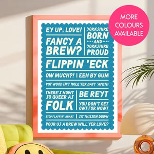 Könnte beinhalten: Ein gerahmter Druck mit einem korallenfarbenen Rahmen. Der Druck hat einen weißen Hintergrund mit blauem Text, der lautet: "Ey Up, Love! Fancy a Brew? Flippin' Eck." Ein rosa Kreis oben rechts sagt "More Colours Available."