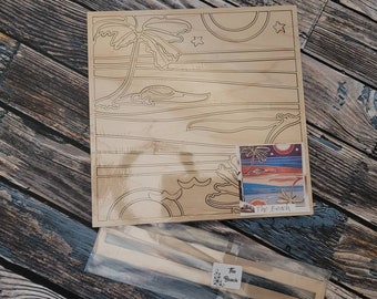Op de afbeelding: Een houten puzzel met een strandscène met een palmboom, zon en golven. De puzzel heeft een rechthoekige vorm en bevat een kleine afbeelding van de voltooide puzzel. De tekst "The Beach" is zichtbaar.