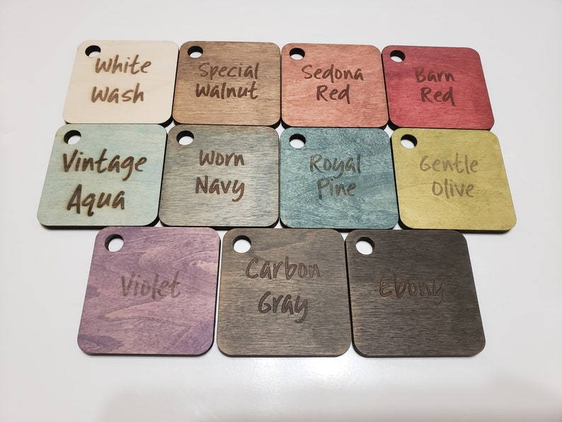 May include: A selection of square wooden colour samples, each with a small hole for hanging. Colours include White Wash, Special Walnut, Sedona Red, Barn Red, Vintage Aqua, Worn Navy, Royal Pine, Gentle Olive, Violet, Carbon Gray, and Ebony.