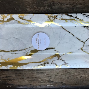 May include: Rectangular paper platters with a white marble design and gold accents. The platters are 7.5 x 16 inches. The packaging includes the text "3 Fine Paper Platters".