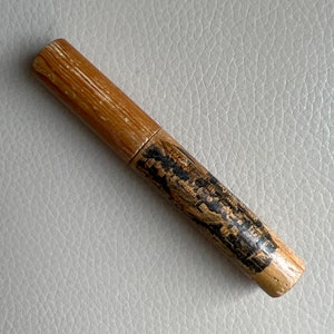 Puede incluir: Un tubo de madera con una imagen en blanco y negro de un edificio y texto impreso en él. El tubo mide aproximadamente 25 cm de largo y tiene un diámetro de unos 2,5 cm.
