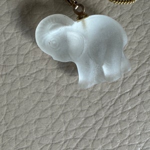 May include: A clear glass elephant charm pendant with a gold chain.