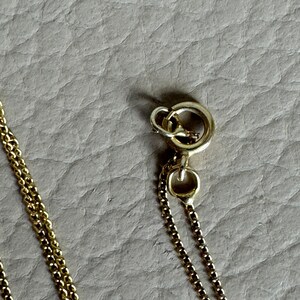 May include: A gold chain necklace with a lobster clasp closure.
