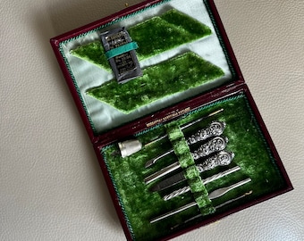 May include: A red velvet-lined sewing kit containing a variety of tools, including a thimble, needles, and a small pair of scissors. The kit is labelled "Registered Sheffield Cutlery".