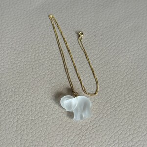 May include: A gold chain necklace with a clear glass elephant pendant.