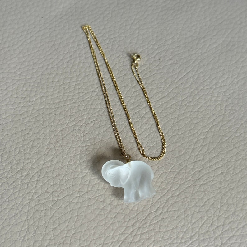 May include: A gold chain necklace with a clear glass elephant pendant.
