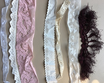 May include: Assortment of white and pink lace trim and a burgundy tassel trim. The lace trims have different patterns and textures.