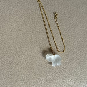 May include: A gold chain necklace with a clear glass elephant pendant.
