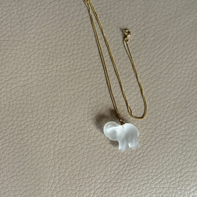 May include: A gold chain necklace with a clear glass elephant pendant.