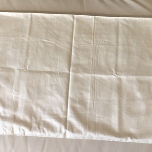 May include: A plain white pillowcase with a smooth, slightly wrinkled surface.