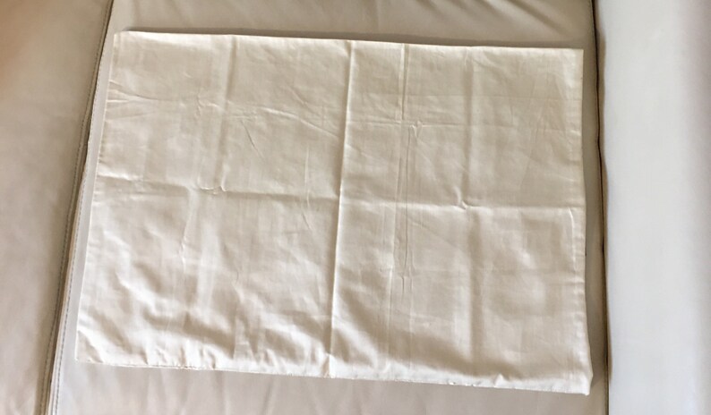 May include: A plain white pillowcase with a smooth, slightly wrinkled surface.