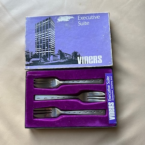 Puede incluir: Un juego de tres tenedores de plata en una caja de terciopelo morado con las palabras "Executive Suite" y "Viners" impresas en la caja.