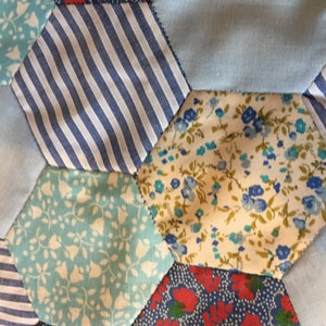 May include: A patchwork quilt made of blue, white, and red fabric with floral and striped patterns.