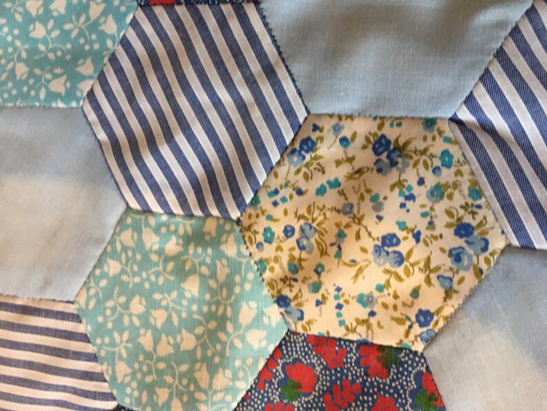 May include: A patchwork quilt made of blue, white, and red fabric with floral and striped patterns.