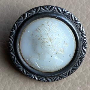Peut inclure: Un bouton en porcelaine blanche avec un motif floral en relief, mont&eacute; dans un cadre en m&eacute;tal argent&eacute; avec un motif de feuilles d&eacute;coratives.