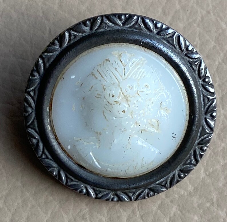 Peut inclure: Un bouton en porcelaine blanche avec un motif floral en relief, mont&eacute; dans un cadre en m&eacute;tal argent&eacute; avec un motif de feuilles d&eacute;coratives.