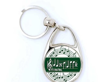 May include: A silver key ring with a green and white circular charm. The charm features a musical note design and the text "It's a Band Thing."