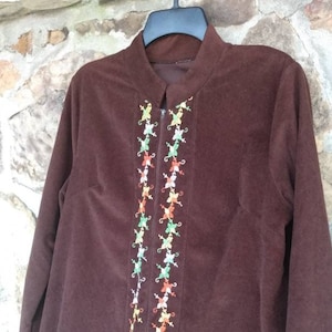 May include: A brown corduroy robe with a long zipper and colorful embroidered flowers down the front.
