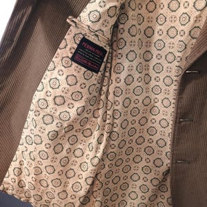May include: Brown corduroy blazer with a patterned lining. The lining has a repeating pattern of small circles and squares. The label inside the blazer reads "PERMA-PREST."