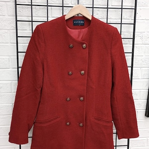 May include: A red double-breasted blazer with gold buttons and two front pockets. The blazer has a round collar and is hanging on a wooden hanger. The brand name "ALEXON" is visible on the label.