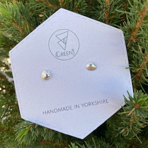 May include: A pair of silver seashell stud earrings on a white card with the text "GREENS" and "HANDMADE IN YORKSHIRE".