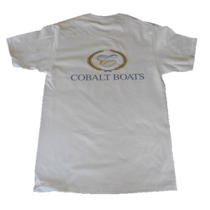 May include: White t-shirt with a blue and gold logo that says "Cobalt Boats".