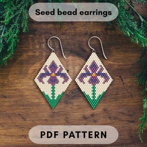 Może przedstawiać: Kolczyki z koralików w kształcie rombu, z fioletowym wzorem kwiatu irysa na kremowym tle. Kolczyki mają srebrne haczyki i zielone łodygi. Widoczny jest tekst "Seed bead earrings" i "PDF PATTERN".