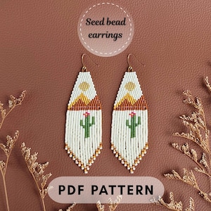 May include: A pair of long, white seed bead earrings featuring a desert landscape design with a yellow sun, brown mountains, and a green cactus with a pink flower. The text Seed bead earrings and PDF PATTERN is visible in the image.